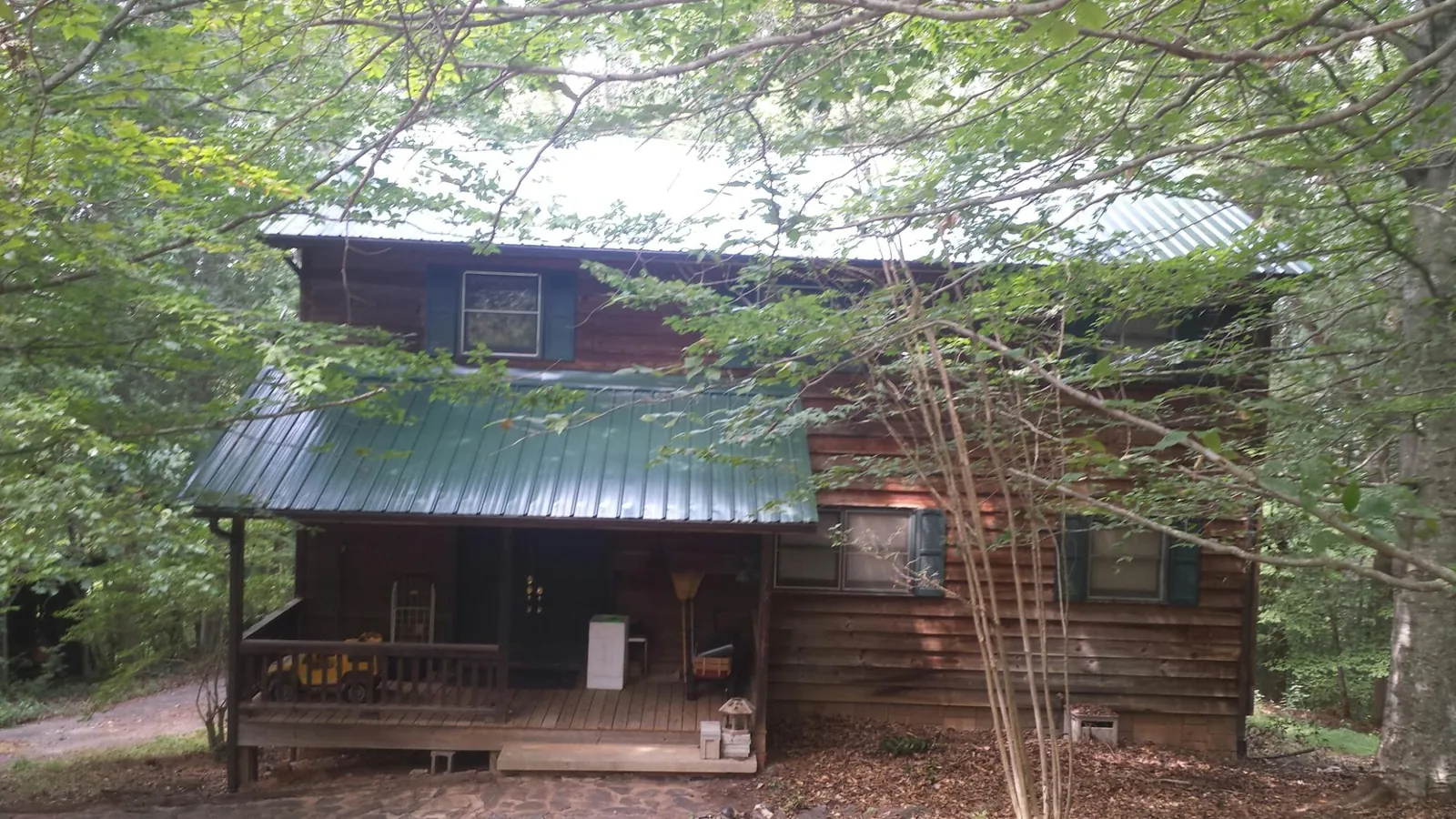 Green metal roof and covered porch on a log cabin in Millbrook