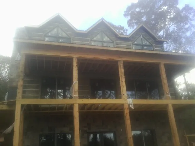 Dormers and porch framing on a large log home under construction — Roof Coating work by our crew in Millbrook